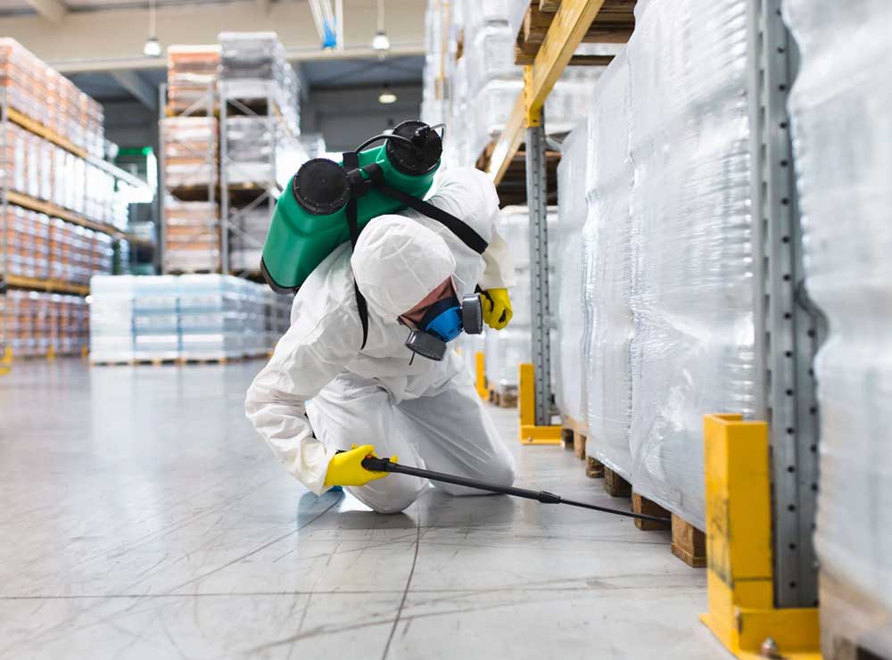 Technician applying EPA-approved sanitizer to commercial kitchen surfaces